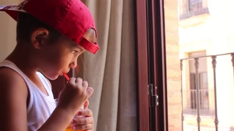 Boy in cap drinking juice through a straw Stock Footage 65300407