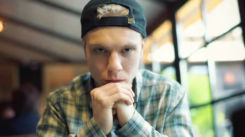 Boy in a cap sitting in the cafe and looking to the camera 動画素材 62408987
