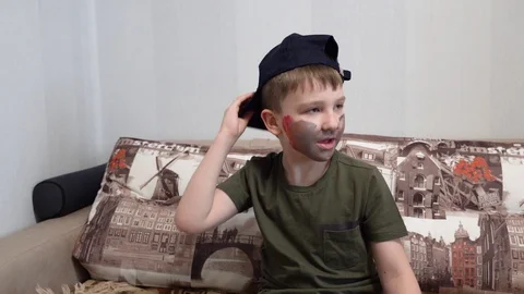 The boy in the cap sitting on the couch shooting his fingers like a cowboy Video stock 127112342