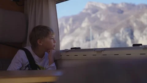 A boy in the car look at mountains through the car window Stock Footage 310229674