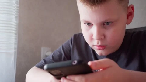 The boy is carefully watching the video on his phone. Stock Footage 260824341