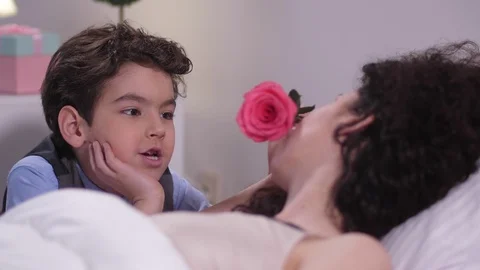 Boy caressing sleeping mom's face with rose Stock Footage 103730406
