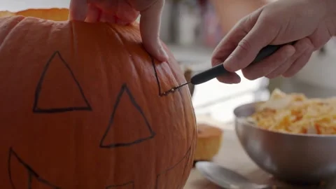 Boy carving Halloween pumpkin at table Concentrating on their Creativity Kids Stock Footage 272458764