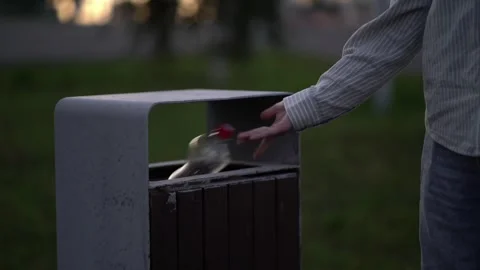 Boy in casual clothes discards plastic bottle into street bin during evening wal Stock Footage 341895026