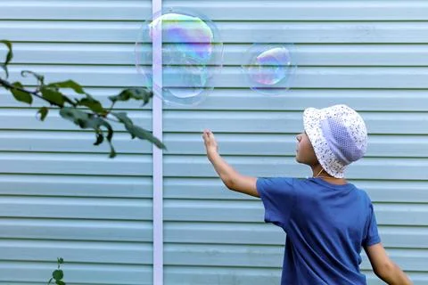 Boy catches large soap bubbles in backyard of country house. Copy space Stock Photos