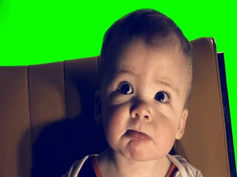 Boy on a chair in front of a green screen. Stock Footage 79865755