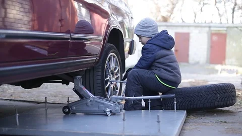The boy changes the wheel. Stock Footage 130002156