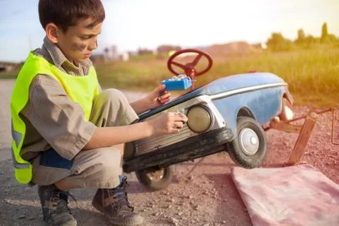 Boy changing light bulbs on his retro toy car Stock Photos