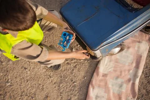 Boy changing light bulbs on his retro toy car Stock Photos