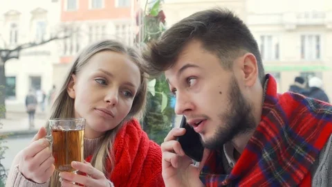 Boy chatting on cellphone while sitting in the cafe with his girlfriend Stock-Footage 71579675