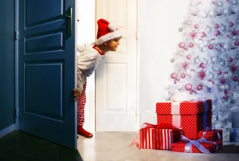 Boy checking presents under Christmas tree Stock Photos