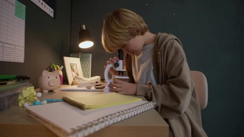 Boy Child Examining Specimen under Microscope at Study Desk Stock Footage 326670785