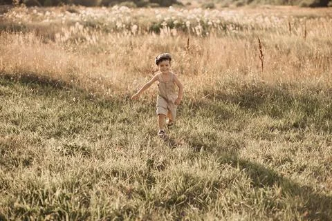 The boy-child is having fun and actively running in the field. A cheerful and Stock Photos