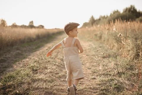 The boy-child is having fun and actively running in the field. A sincere and Stock Photos