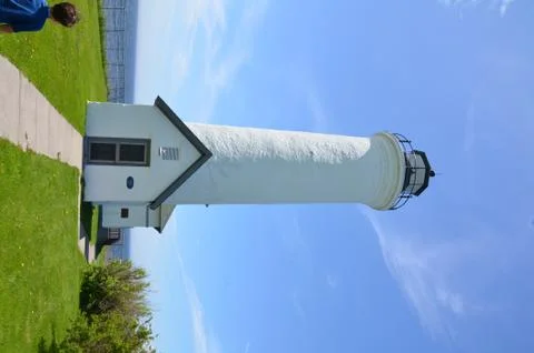 Boy child looking at white lighthouse and water Stock Photos