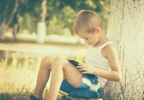 Boy child playing with tablet pc outdoor with summer nature on background com Stock Photos