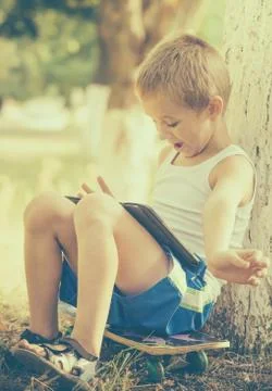 Boy child playing with tablet pc outdoor with summer nature on background com Stock Photos