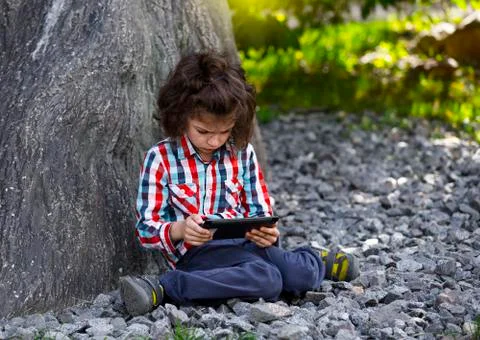 Boy Child playing with Tablet PC Outdoor with forest on background Computer G Stock Photos
