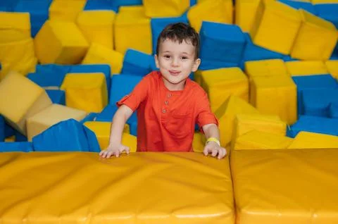 A boy child plays in a pool with soft cubes,. A child in a game entertainment Stock Photos