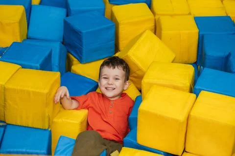 A boy child plays in a pool with soft cubes,. A child in a game entertainment Stock Photos