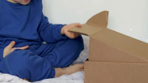 Boy child preschooler opens gift cardboard box with christmas toys 库存影片 220334600
