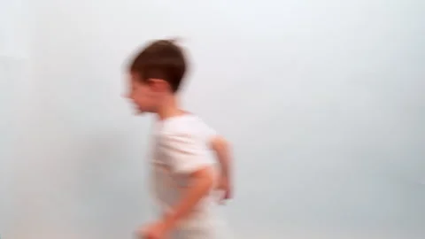 Boy child running along white studio background. Motion blur effect for dynamic Stock Footage 340407130