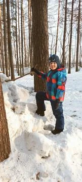 Boy child stands on a mountain of snow stones and looks into the camera Stock Photos