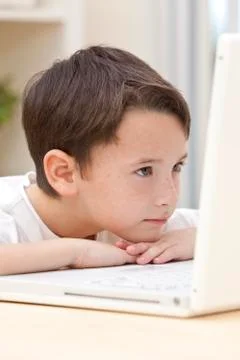 Boy child using laptop computer resting on his hands Stockfoto's