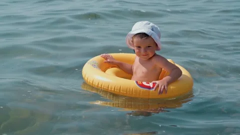 A boy child in a yellow swimming circle is drifting on the waves in the sea. The Stock Footage 192988816