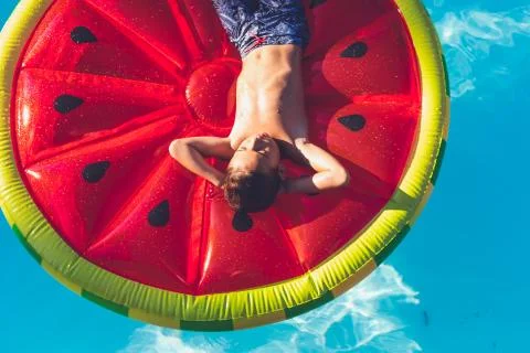Boy chilling in pool on watermelon float Stock Photos