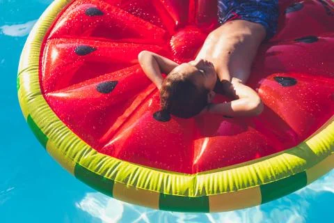 Boy chilling in pool on watermelon float Stock Photos
