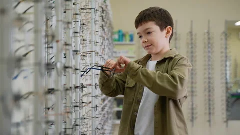 Boy choosing eyeglasses in optical store Video stock 310811777