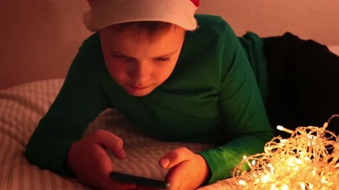 A boy with Christmas decorations lying on the bed at night Stock Footage 165395587