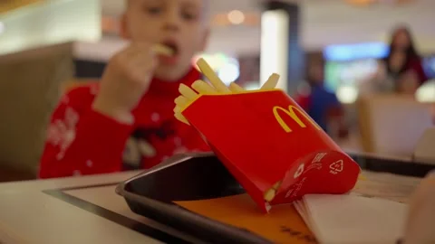 Boy in Christmas sweater eats French fries at McDonald's in the mall. Food-court Stock Footage 166834845