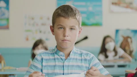 A boy in a classroom putting on a protective mask. Post quarantine school, ne Stock Footage 137554050