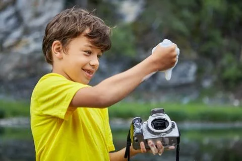 Boy cleans CMOS image sensor in digital camera. Stock Photos