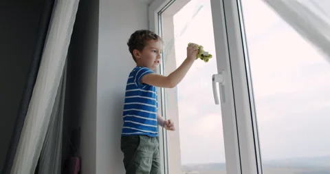 A boy cleans a window with a cloth and sponge, showing enthusiasm Video stock 306673142