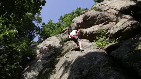 Boy climber rappelling down with the help of a belayer Stock-Footage 80864583
