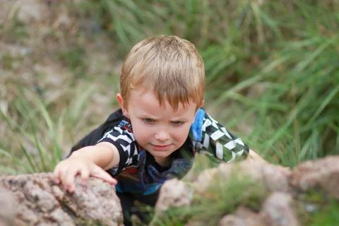 Boy climbing up boulder Stock Photos