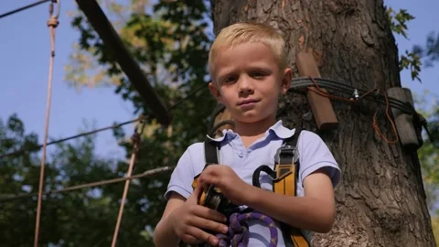 A boy in climbing gear in a rope park, holding a carbine and showing a thumbs up Stock Footage 228733141