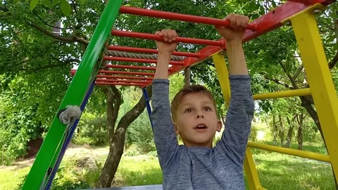 Boy climbing monkey bars on jungle gym outdoors during summer. Stock Footage 245363404