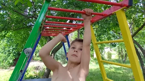 Boy climbing monkey bars on jungle gym outdoors during summer. Stock Footage 245583239