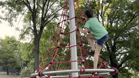 Boy climbing net in the outdoor park child playground Stock Footage 217700358