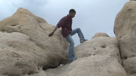 Boy climbing rock formation. Video stock 27344197