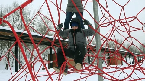 Boy climbing ropes on the playground in winter Stock Footage 107533976