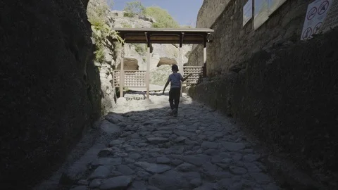 A boy climbs the ancient stone pavement in the cave town. Crimea, Chufut Kale. Stock Footage 94848795