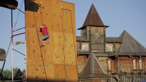 Boy climbs up a climbing mountain Stock Footage 82364878