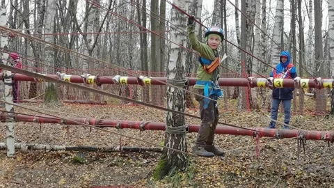 The boy climbs parallel ropes through the ravine Stock-Footage 163895977