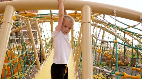 A boy climbs a rope on a slide on a playground in a modern residential complex. Stock Footage 315093808
