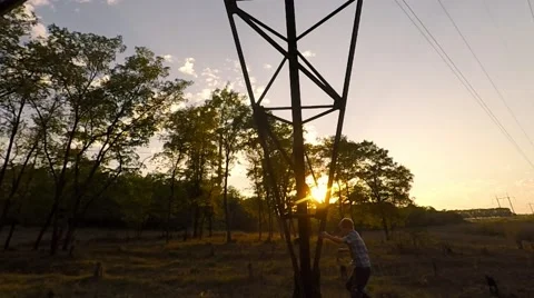 A boy climbs on a support against the sunset. 库存影片 55570995